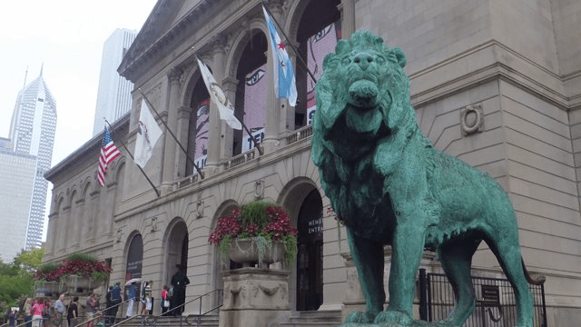 Photo of the front of the New York Public Library. Bronze lion in foreground.